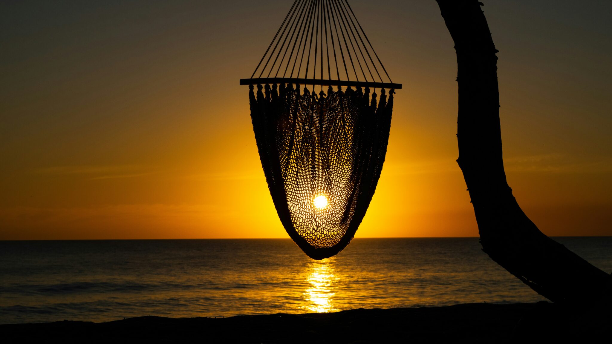 Hamaca vacía frente al mar al atardecer, símbolo del descanso en vacaciones sin autoexigencia